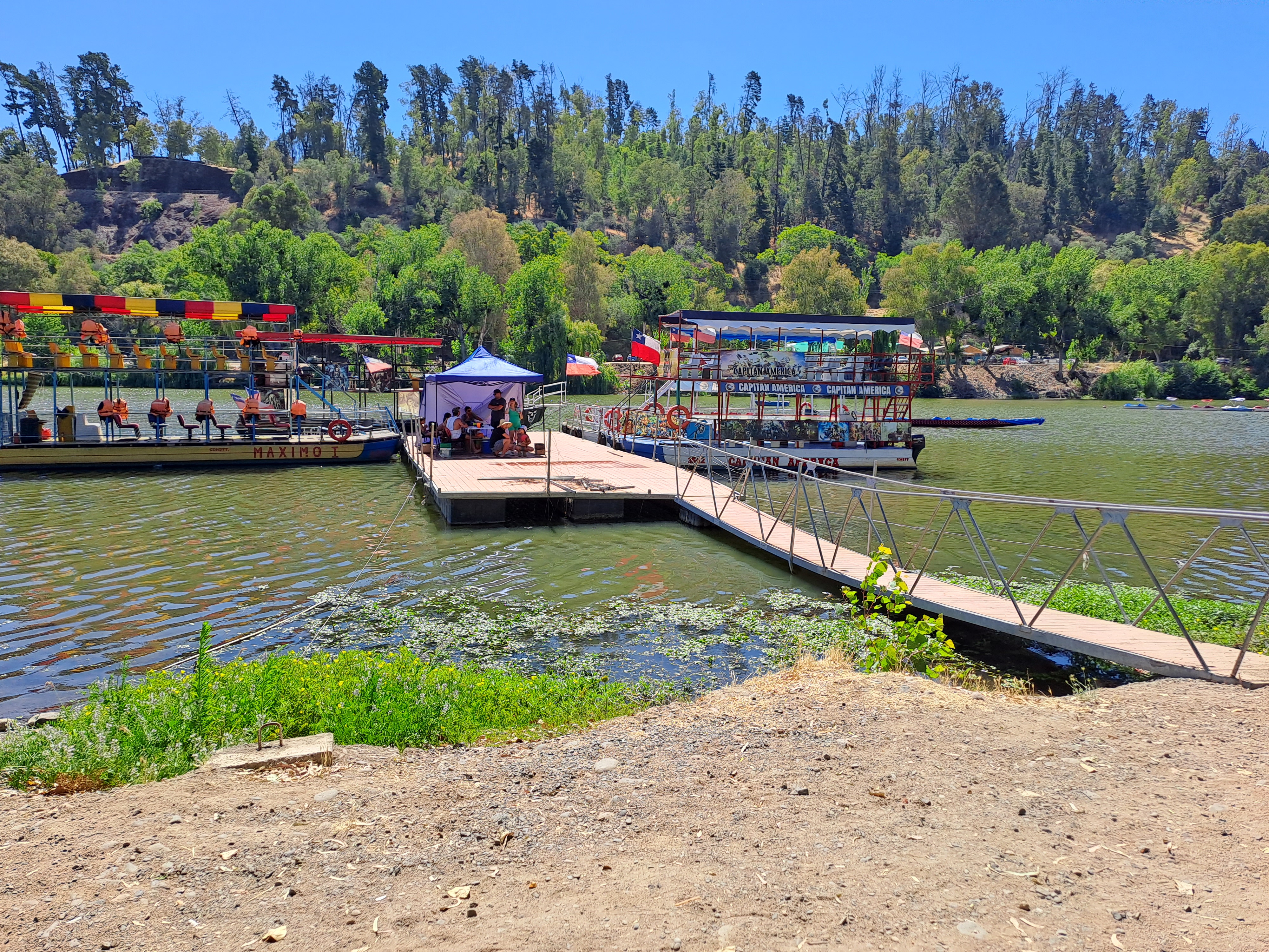 Fotografía del río, cuenta con borde de tierra y un puente para llegar a subir a los botes que ofrecen el servicio de un paseo por el río